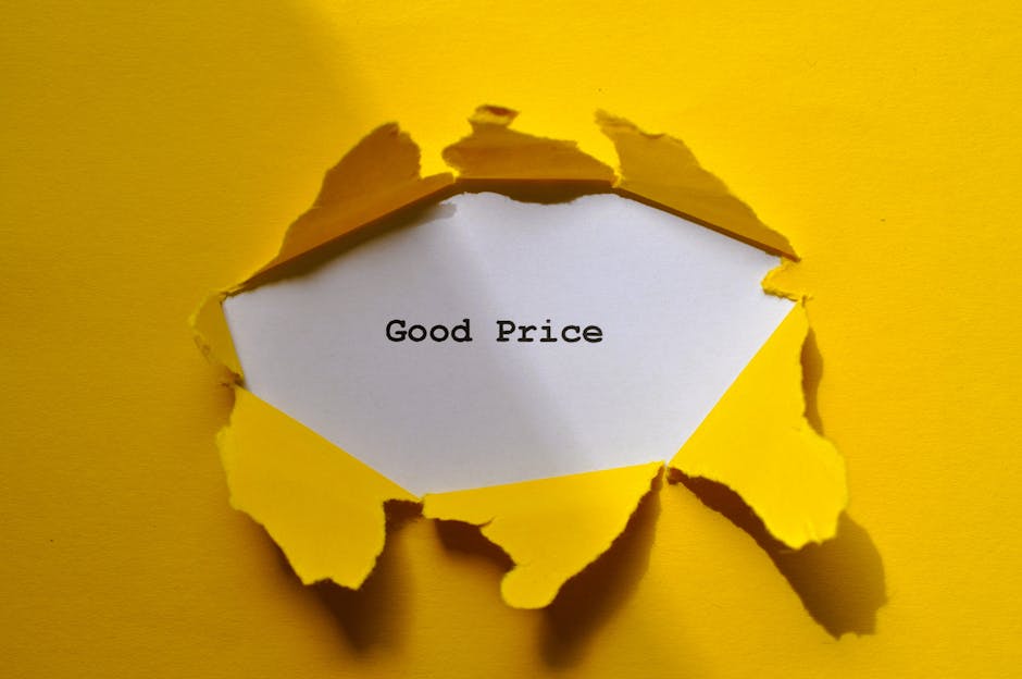 A torn piece of yellow cardboard with jagged edges reveals a white paper inside that has the message 'Good Price' typed in black text. The cardboard is torn outward from the centre, exposing the message clearly, and the background is a solid yellow surface. The image visually suggests themes of pricing, affordability, or negotiations related to house removals or moving services, aligning with moving logistics and home relocation processes that might be covered by Man with Van Harefield on their website page about avoiding price scams and tips for accurate removal quotes.